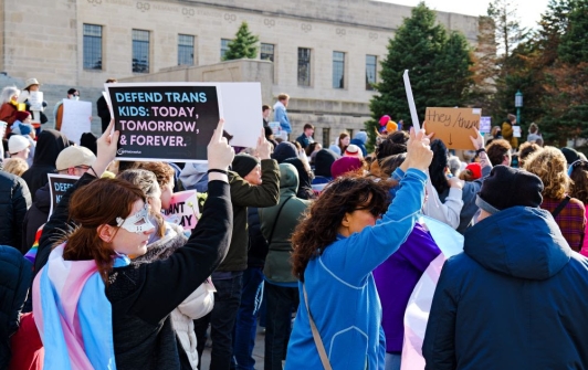 A crowd outside the Nebraska Capitol holds signs reading "Defend Trans Kids"