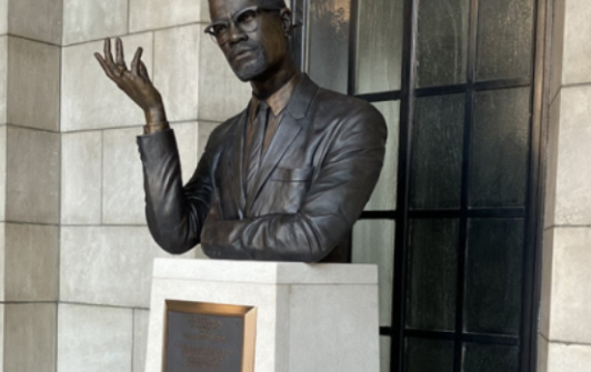 A bronze bust of Malcolm X sits atop a white pillar