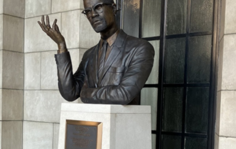 A bronze bust of Malcolm X sits atop a white pillar