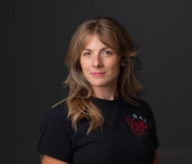 Headshot of a women with shoulder-length blonde hair and a black t-shirt with the word "vote" in red