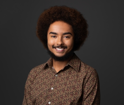 Headshot of a man with a short beard in a brown floral button-up shirt