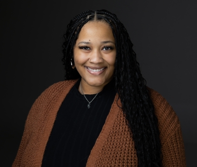 Headshot of a woman with long dark hair wearing a black shirt and brown cardigan