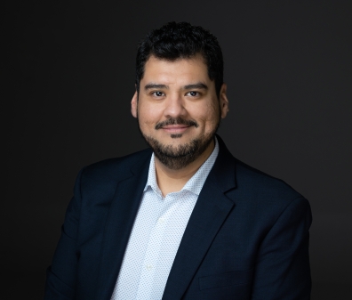 Headshot of a man with a beard in a navy blazer and light blue shirt