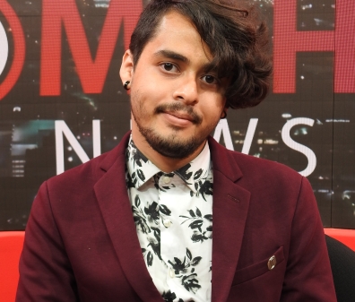 Headshot of a person in a burgundy blazer and white and black button up shirt